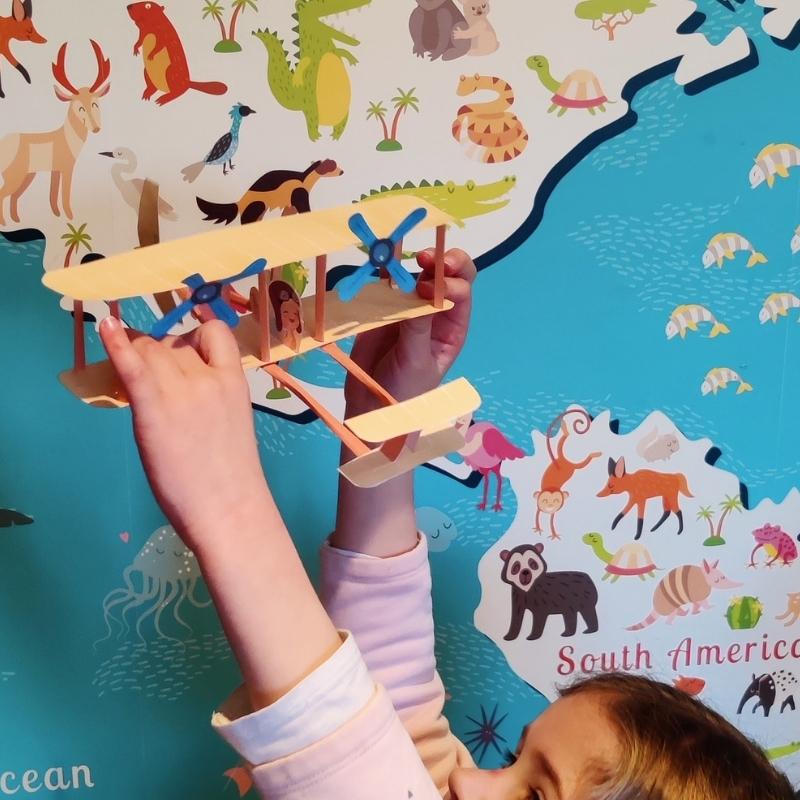 Paper adventure wright brothers plane model. Fun print-at-home activity for curious children. View of paper model lifted in air by child